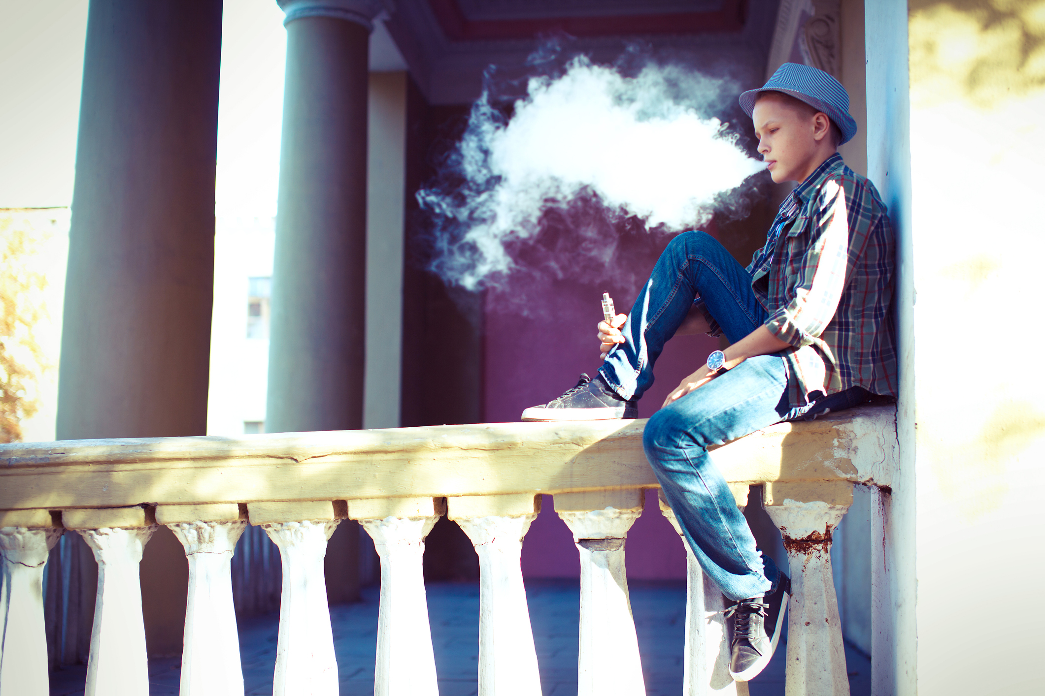 Teen sitting on railing vaping
