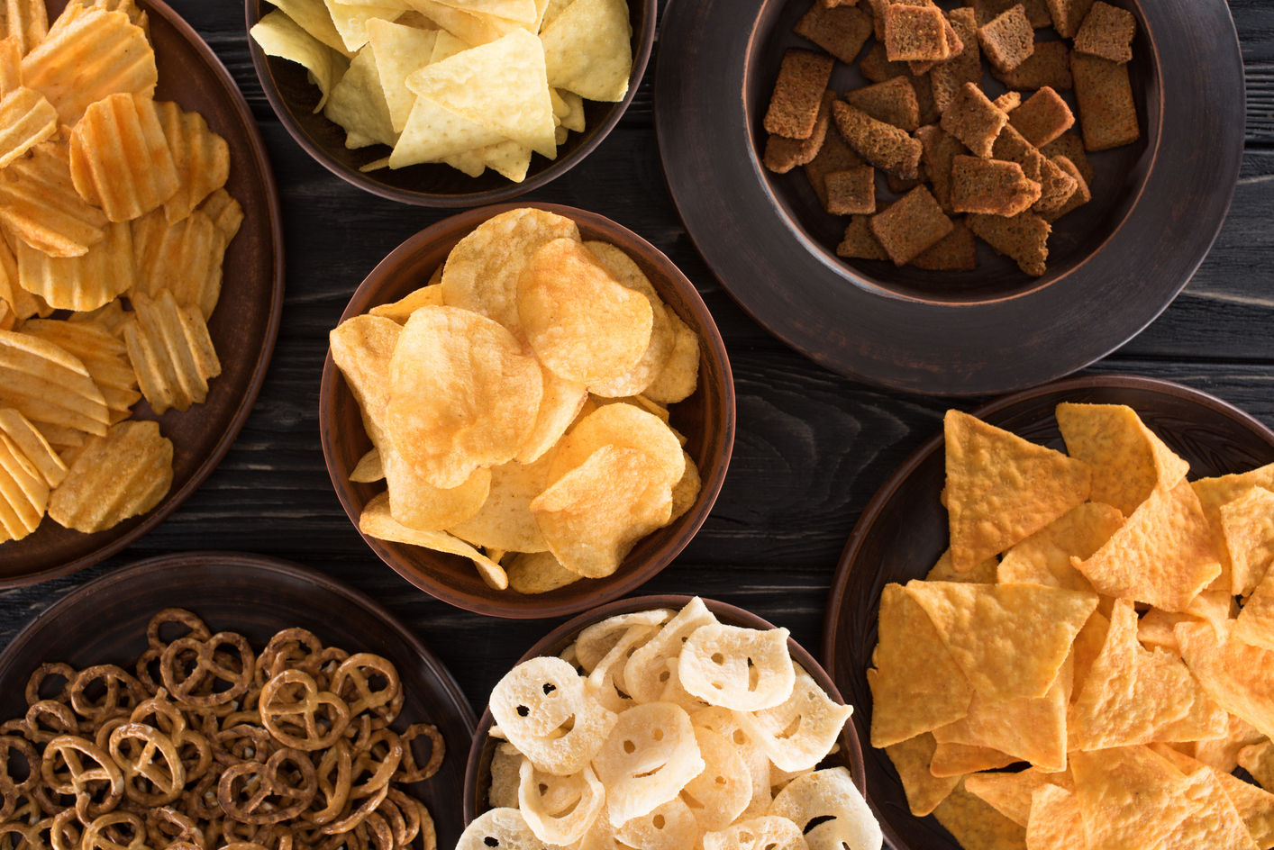 Chips, pretzels, and other snacks on a table.