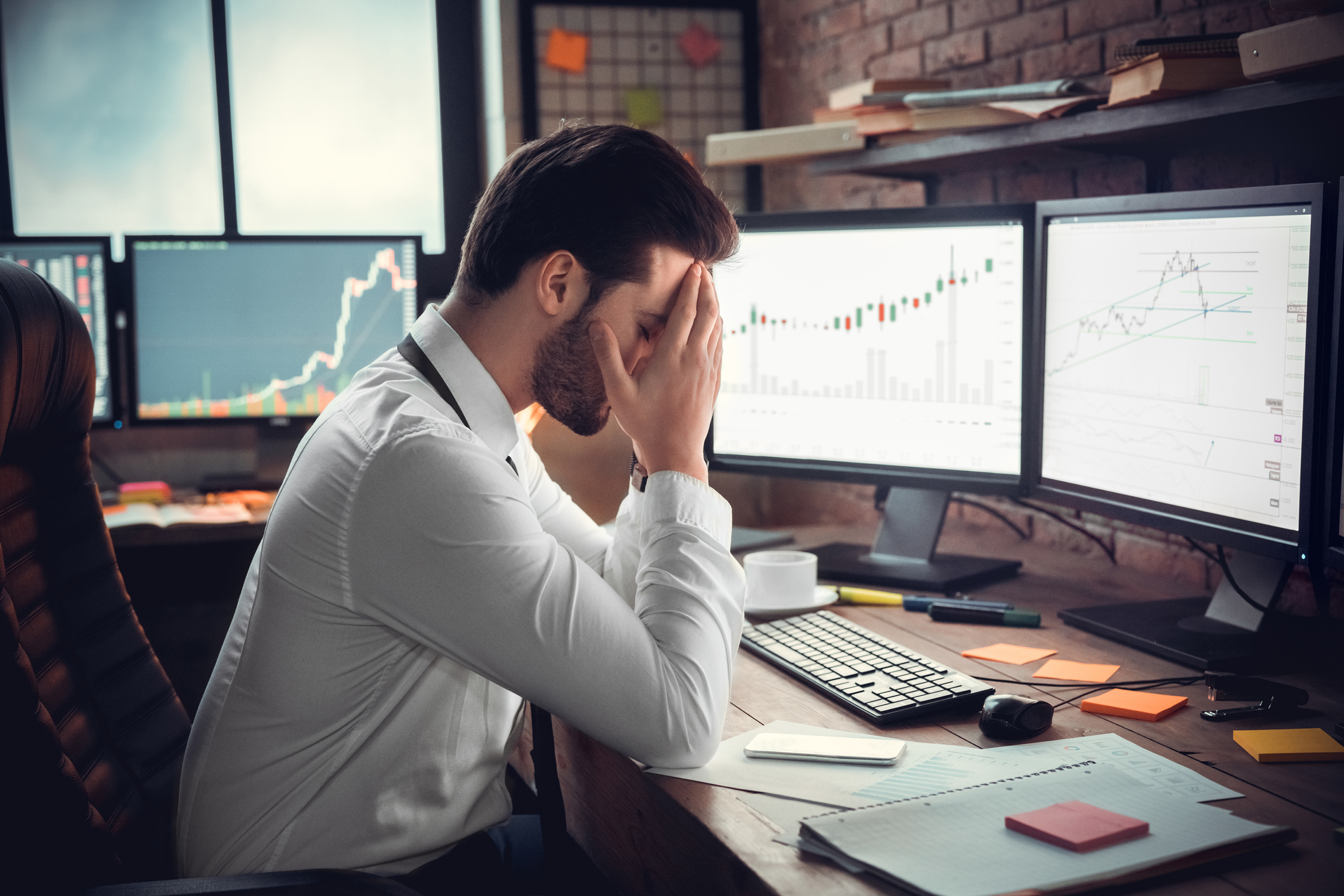 A stressed-out investor looks at a trading screen.
