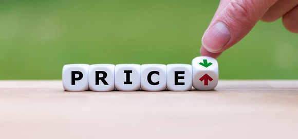 Letters on blocks spelling out PRICE, with the final block tipped to show a green and a red arrow.