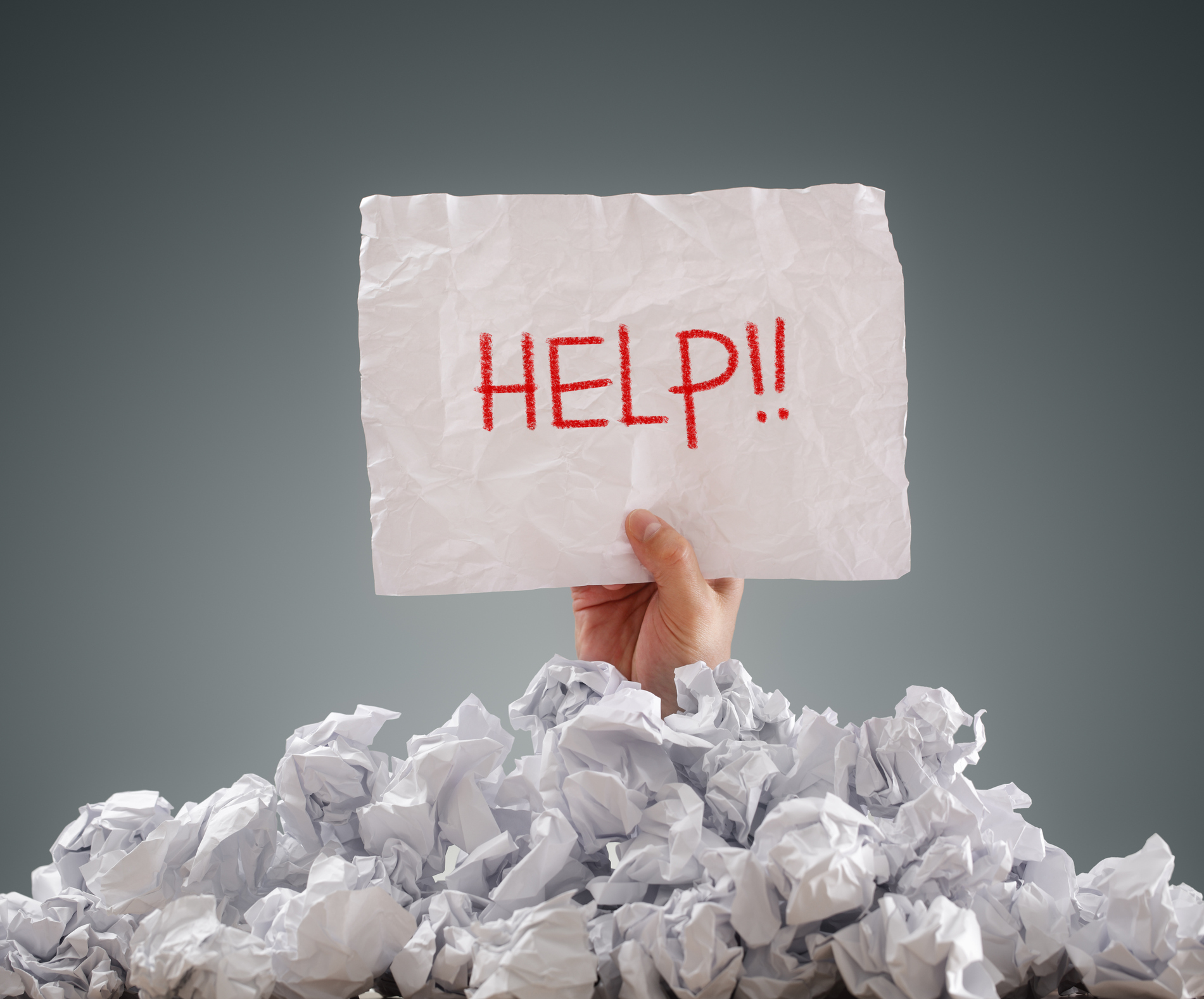 person buried under paper holding help sign