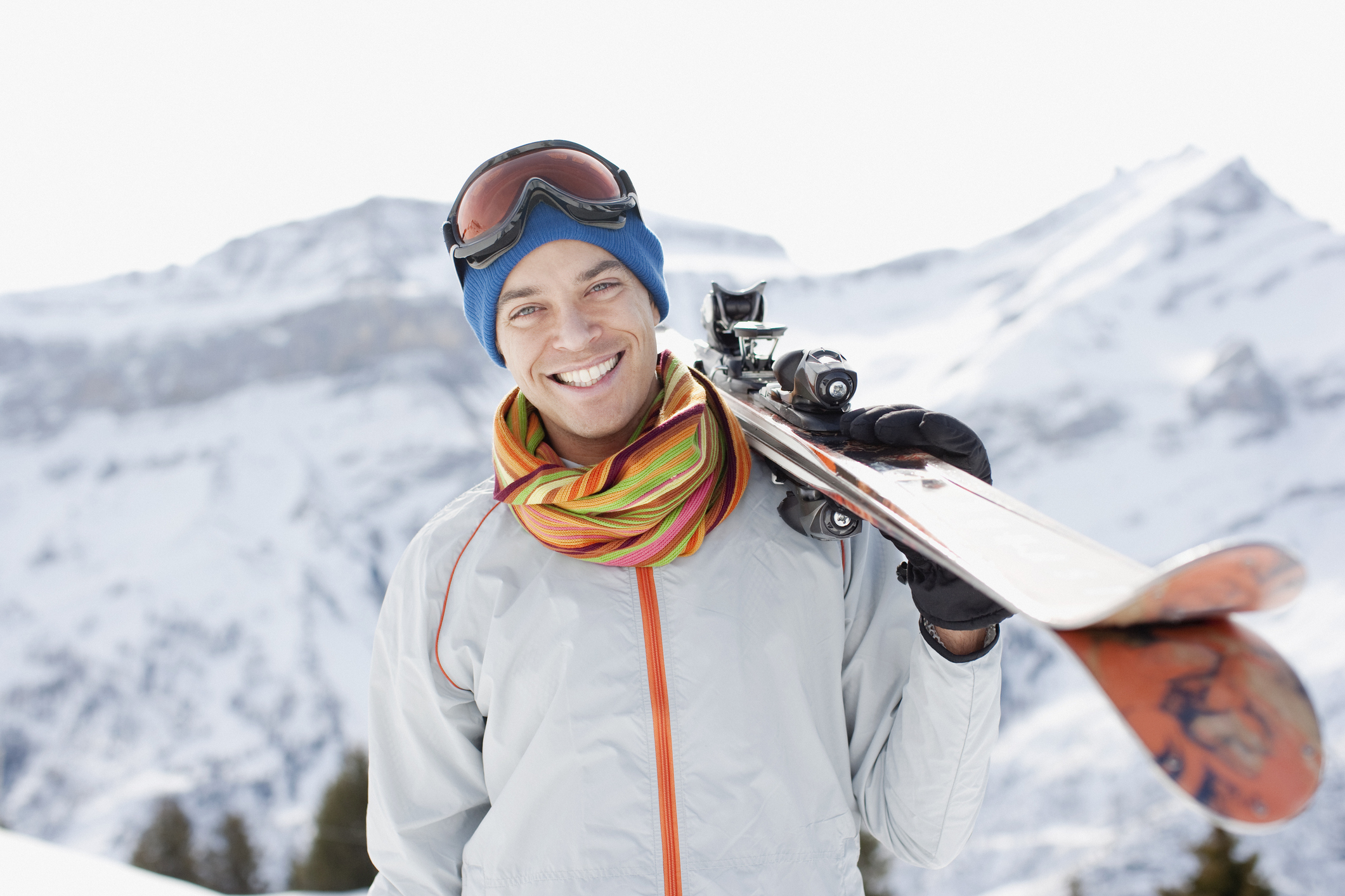 A man holding skis on top of a mountain run.