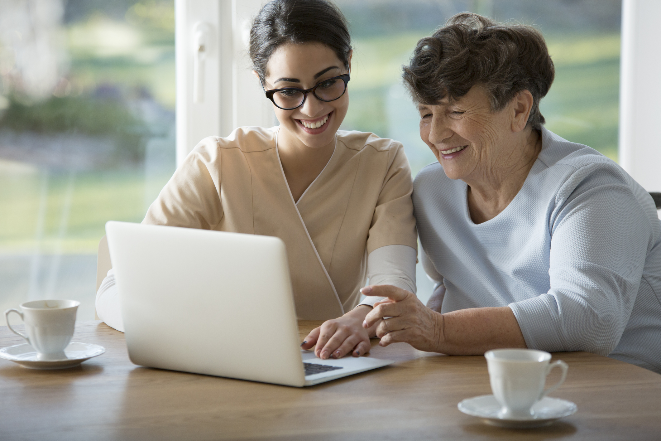 Smiling assistant sitting next to elderly woman