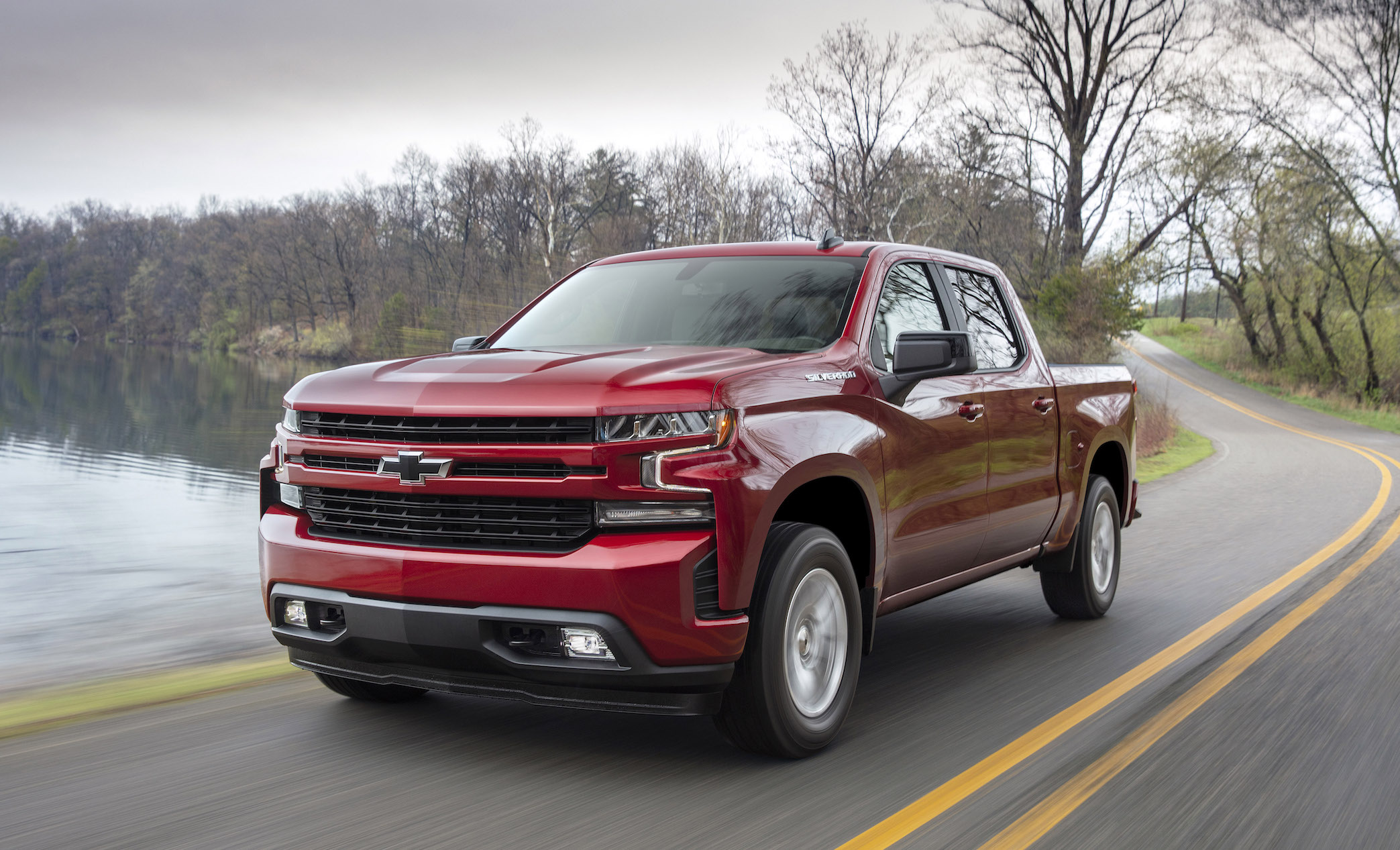 A red 2019 Chevrolet Silverado 1500, a light-duty full-size pickup truck, on a road near a lake.