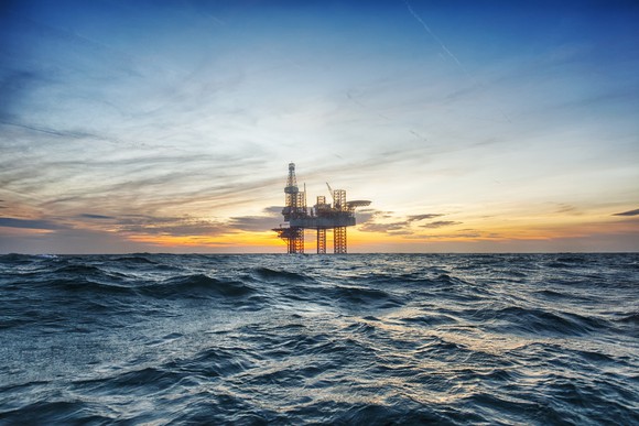 An oil refinery in the middle of an ocean with a clear sky in the background.