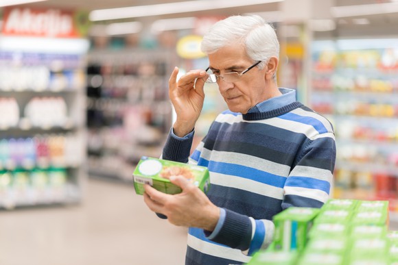 Older man in a supermarket adjusting eyeglasses