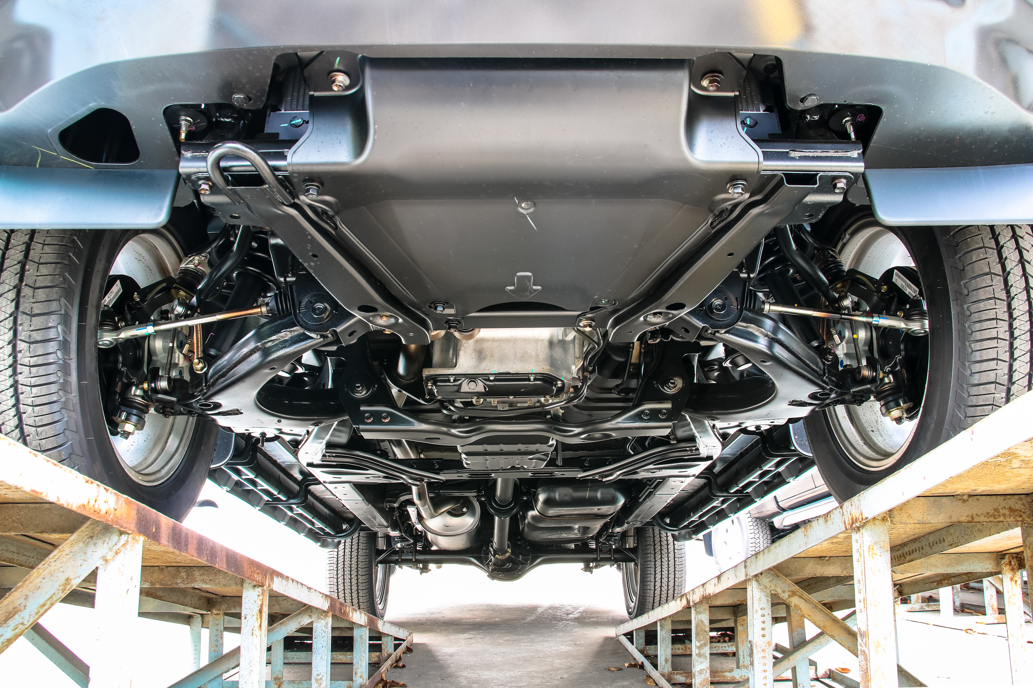 A car sitting on a ramp with a clear view of the drivetrain underneath.