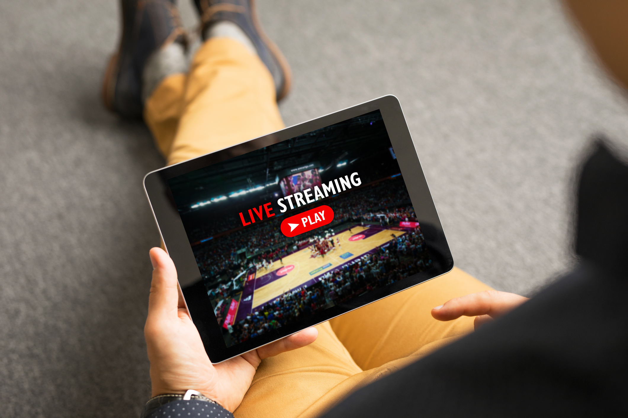A man streams a live NBA game on a tablet.