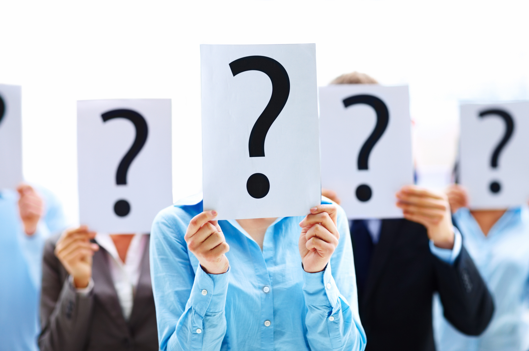 Several people holding pieces of paper with question marks in front of their faces