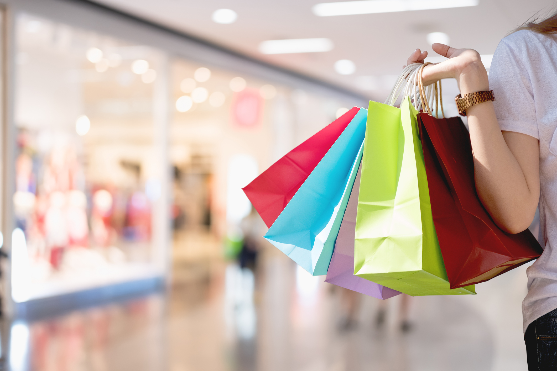 A young woman carrying bags in different colors in a shopping mall.