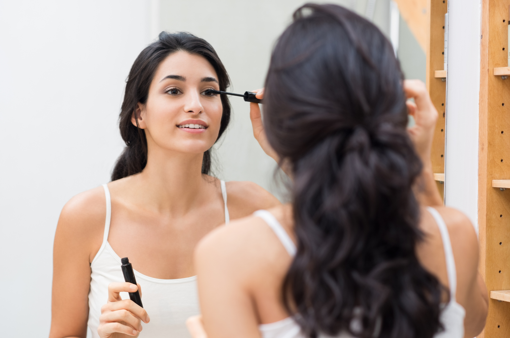A woman putting on mascara.