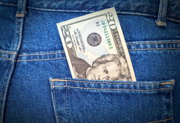 A $20 bill sticking out of a back pocket of blue jeans.