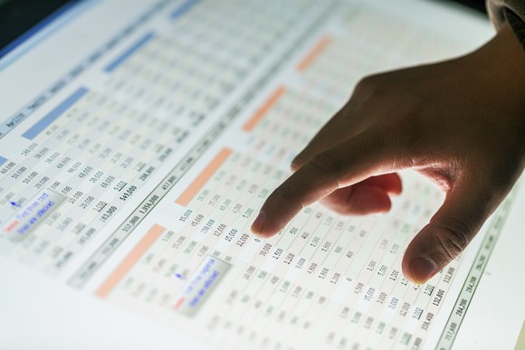 Someone's finger pointing to numbers on a spreadsheet.