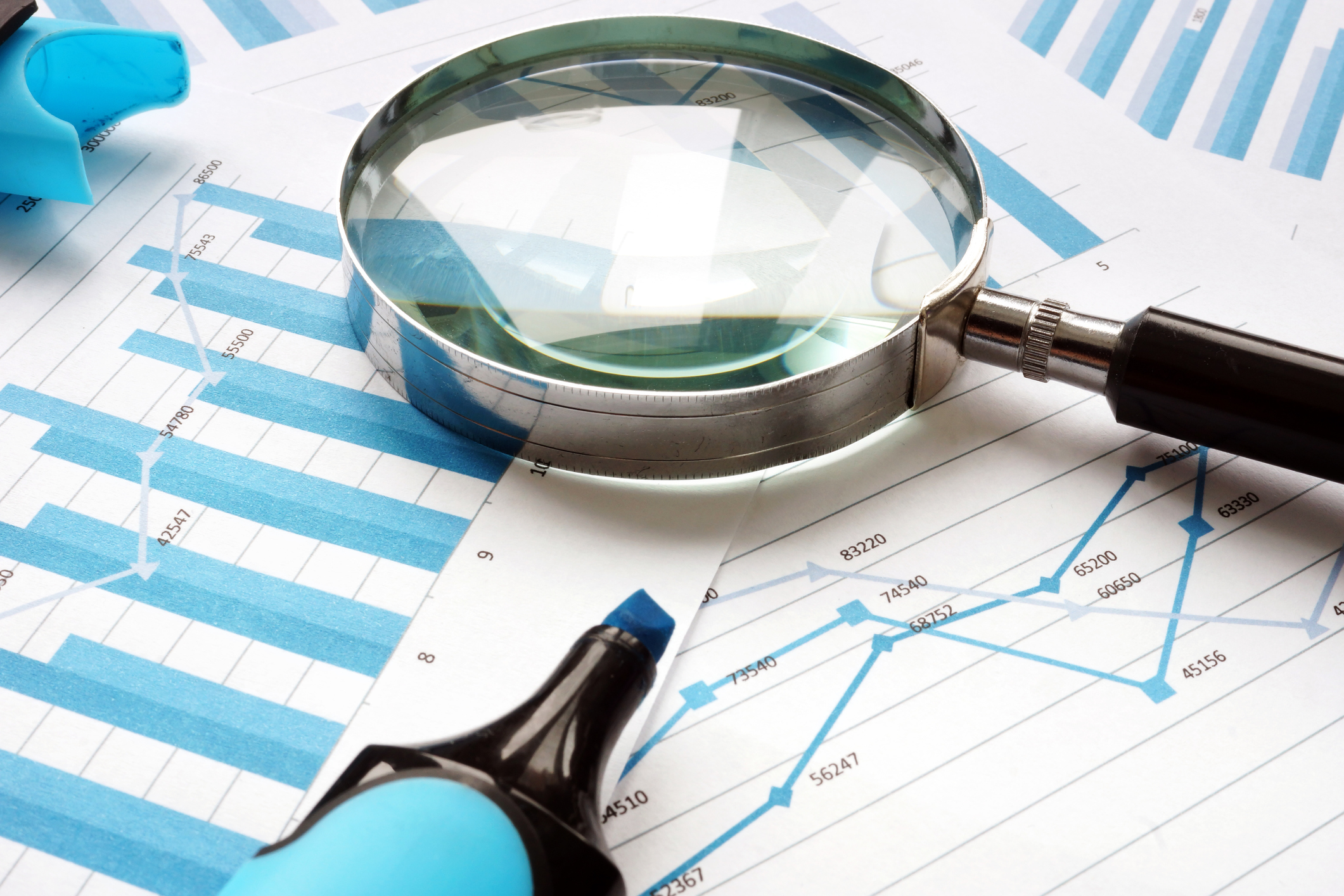 Magnifying glass on top of charts.