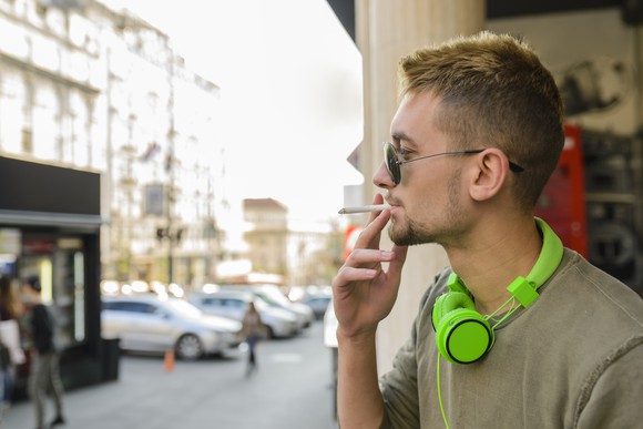 Man with green headphones smoking a cigarette