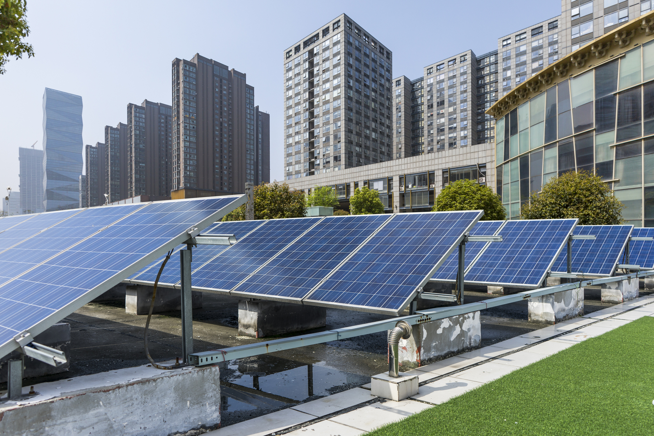 Rooftop solar panels on an office building, with modern office buildings in the background.