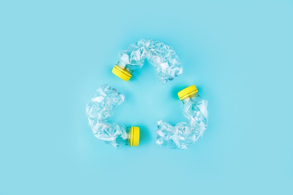 Three bent plastic bottles arranged in the shape of a symbol for recycling