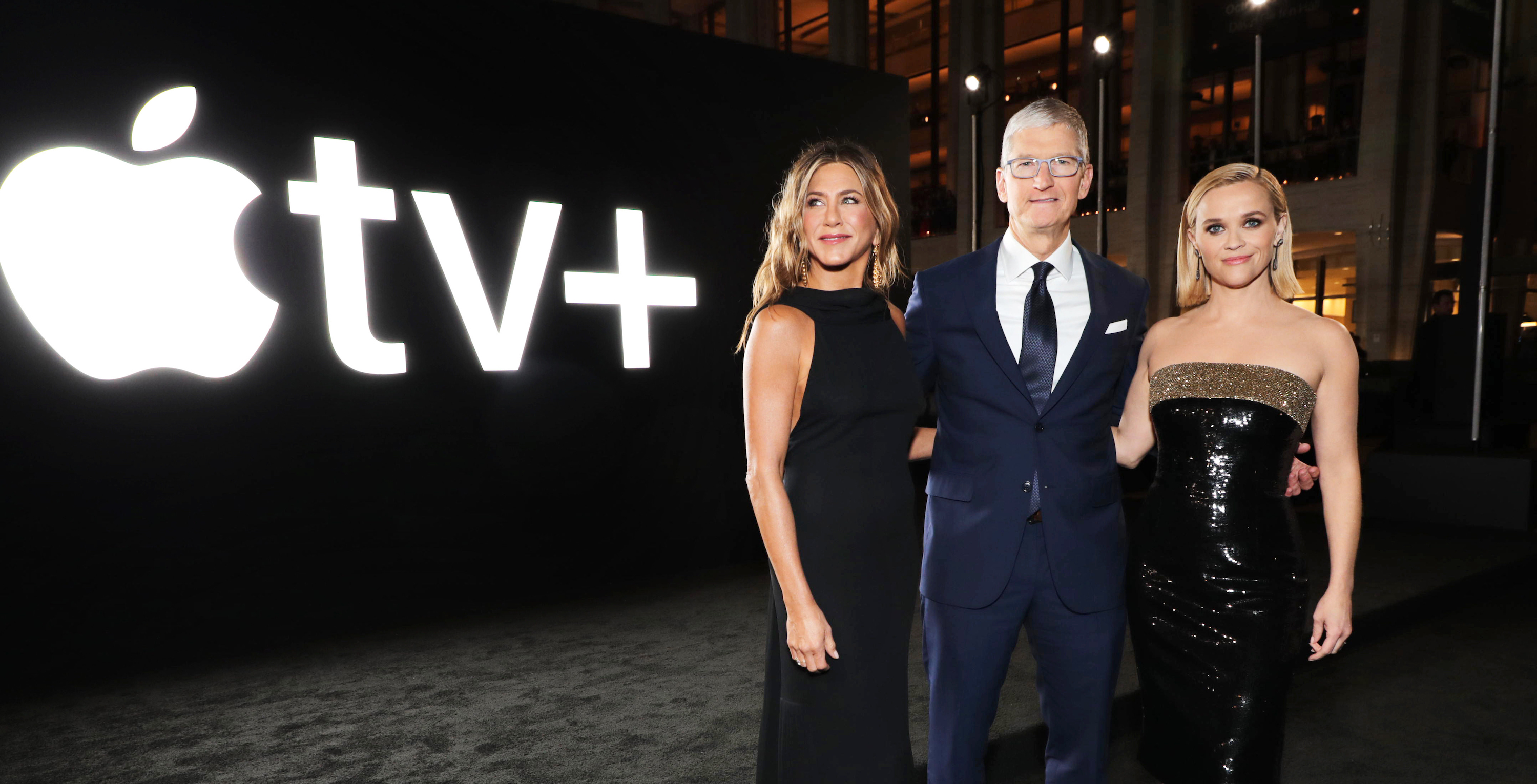Jennifer Aniston, Tim Cook, and Reese Witherspoon in front of the Apple TV+ logo