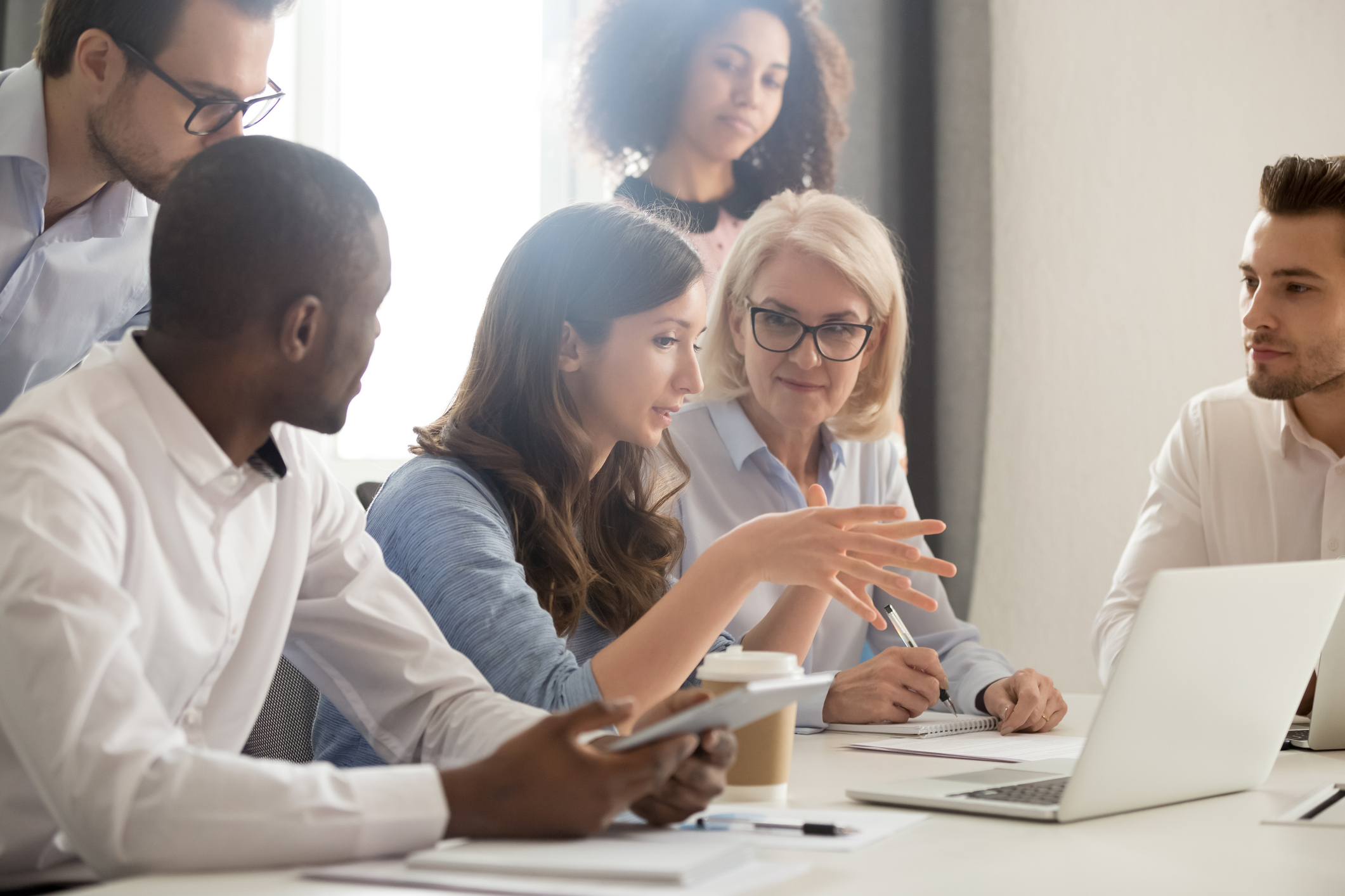 Business woman sitting at a laptop while meeting with employees