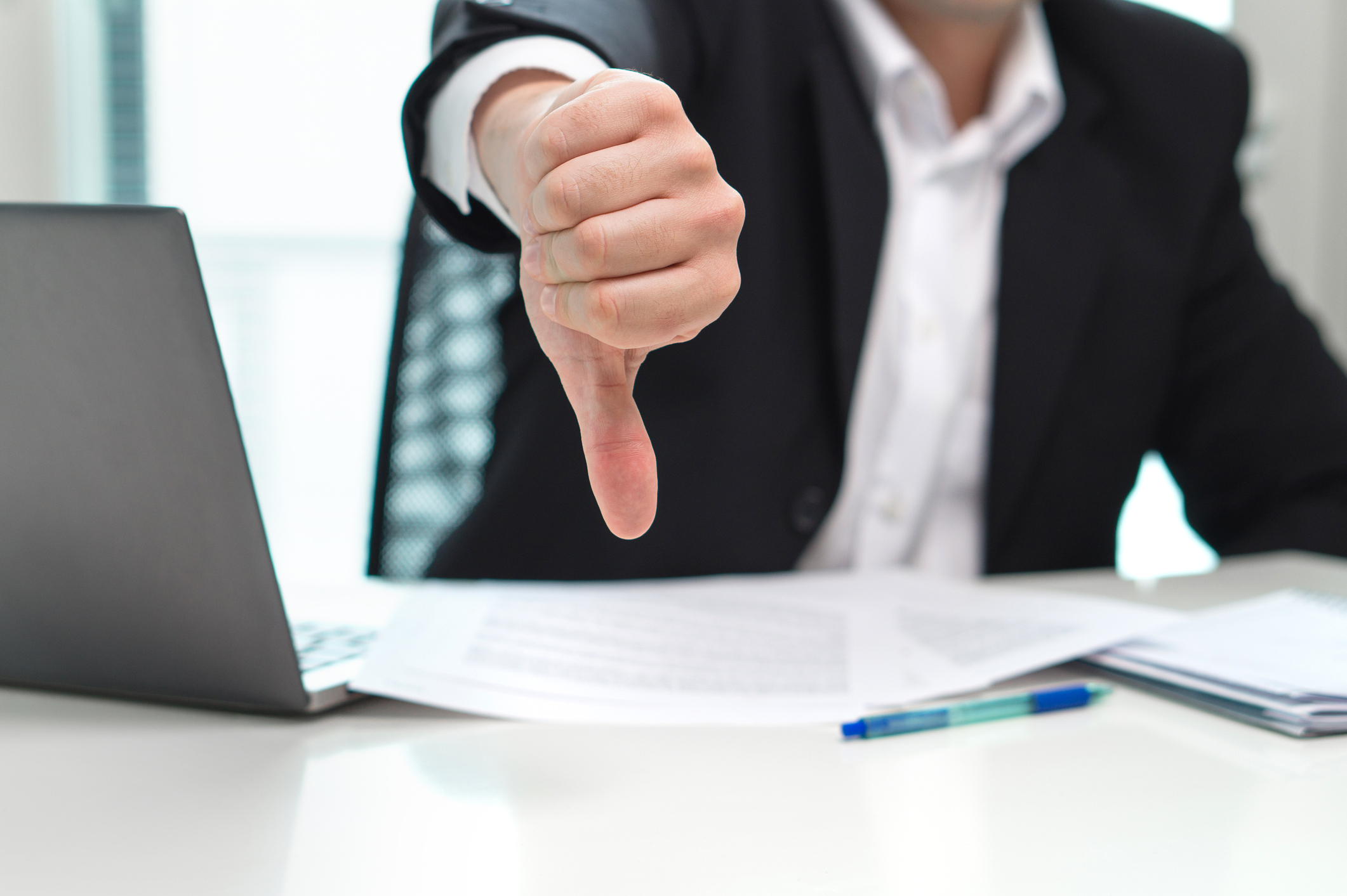 Businessman with laptop giving the thumbs-down.