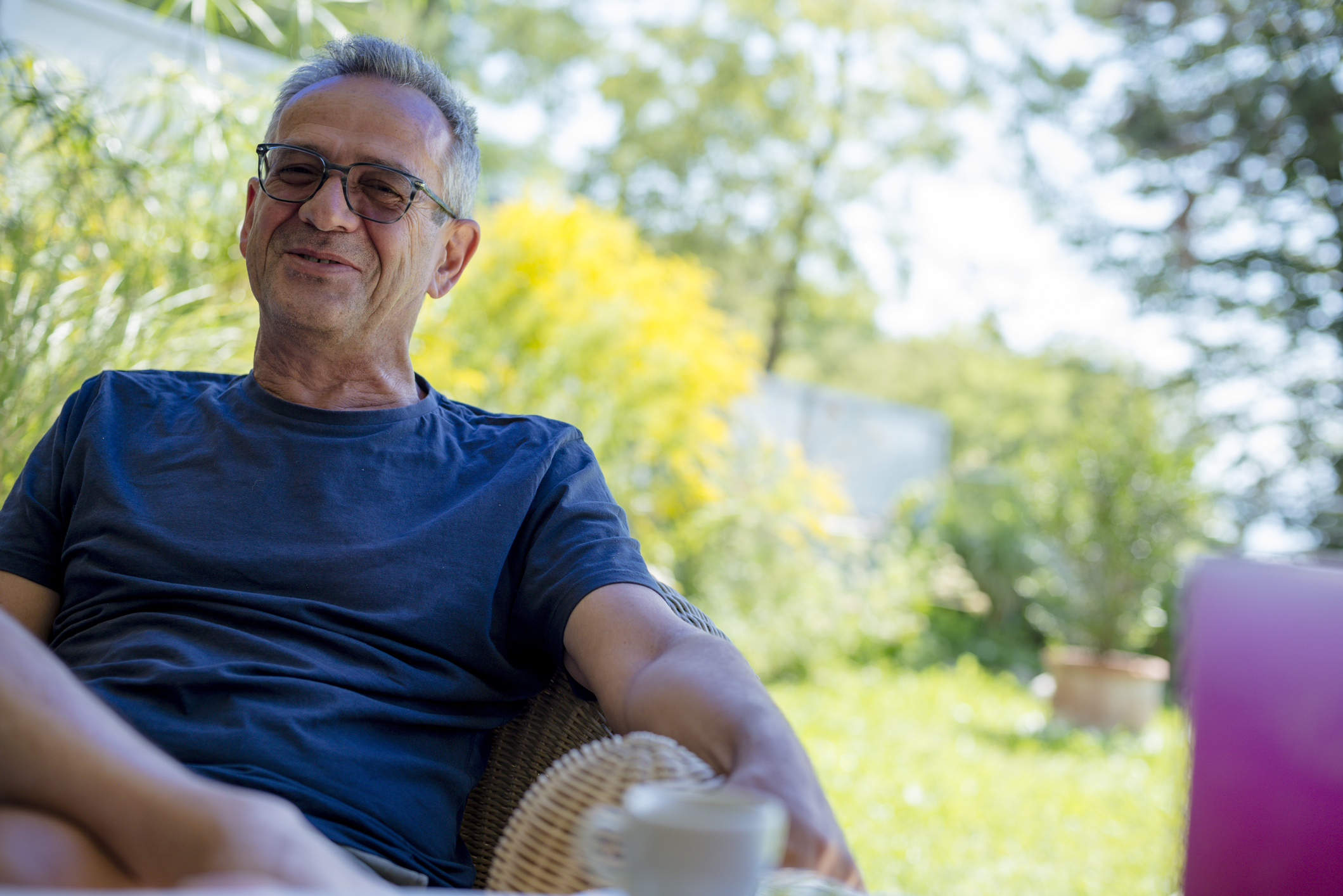 Smiling older man sitting in a chair outdoors