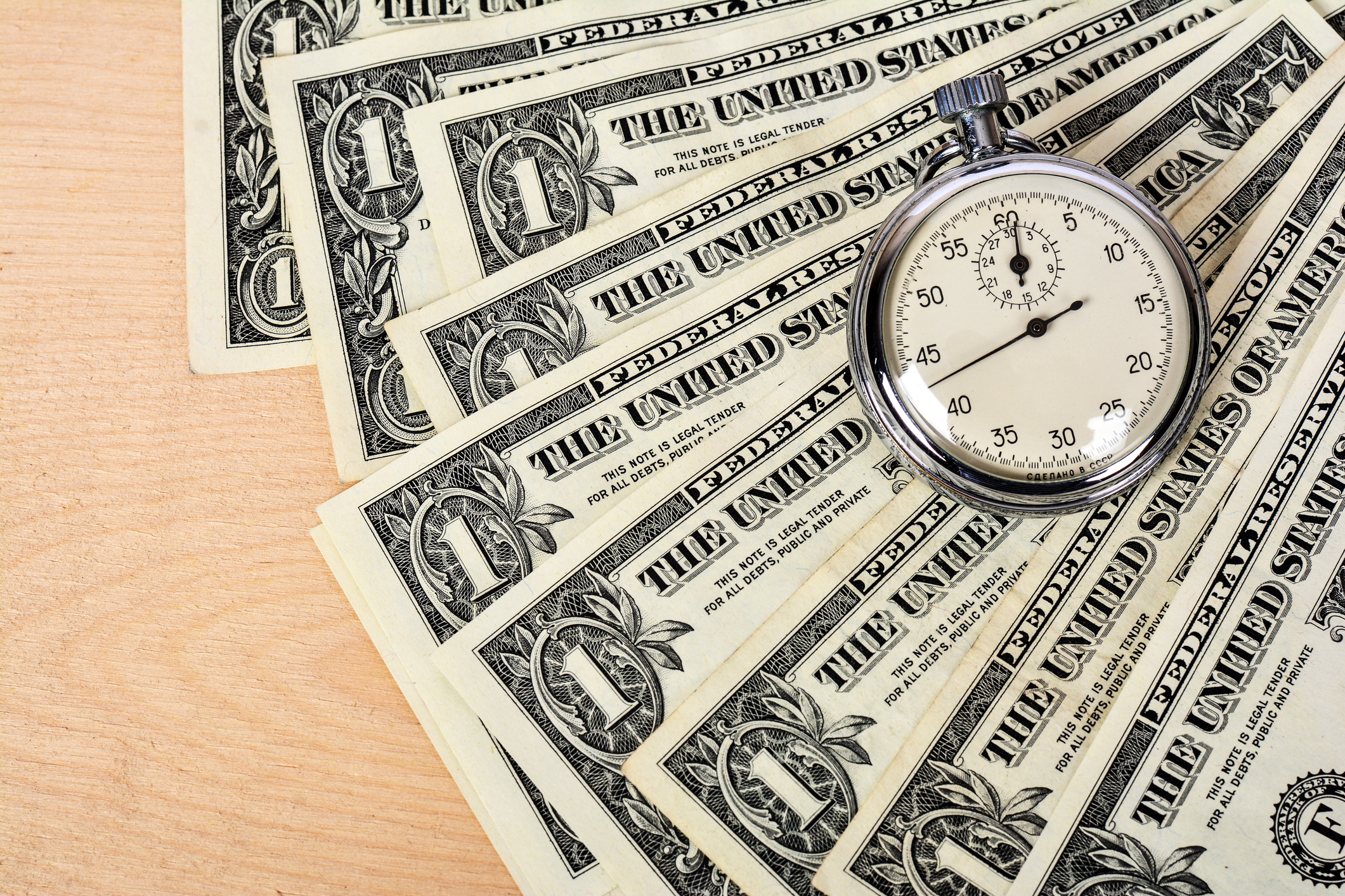 Dollar bills with a stopwatch on top of them.