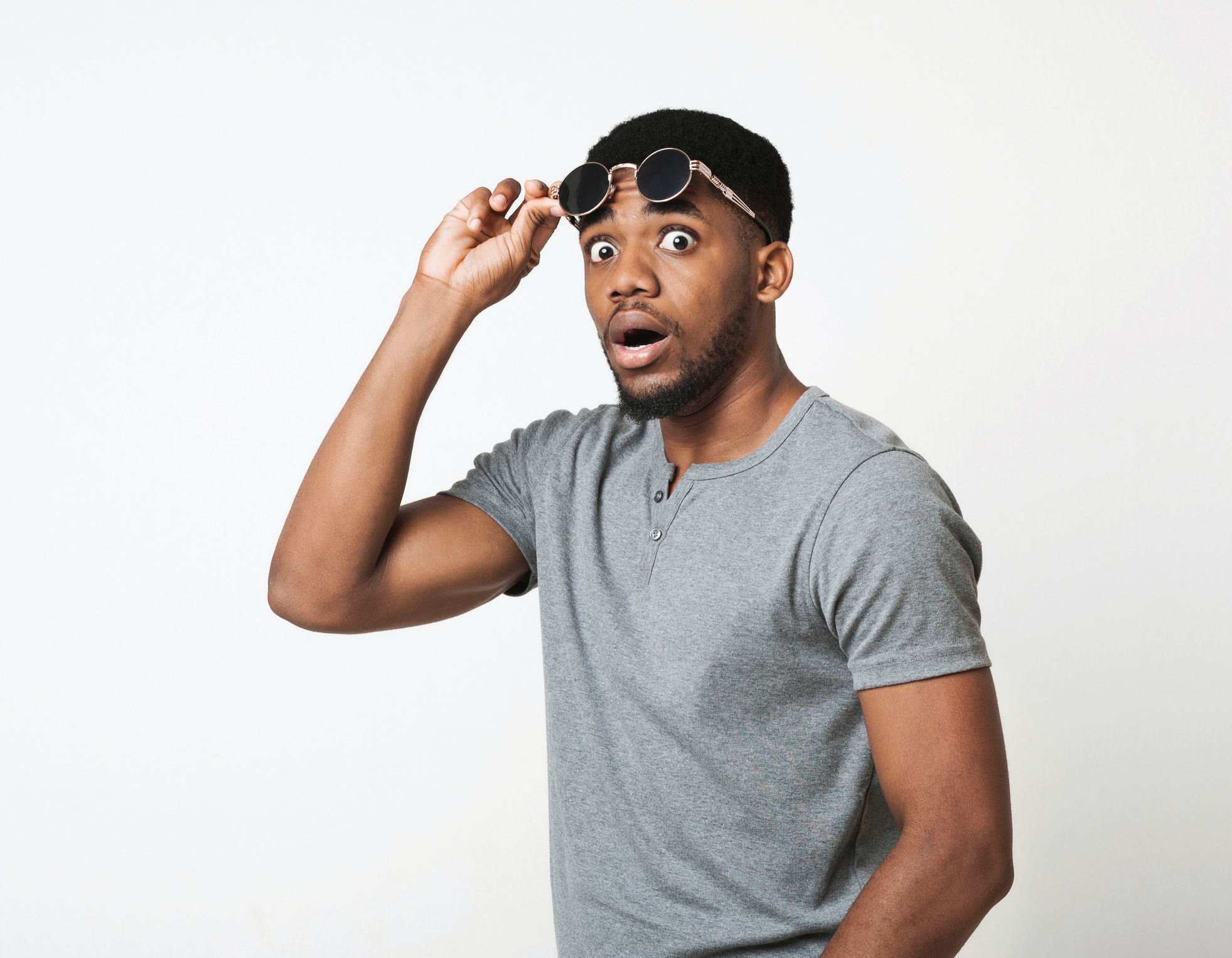 Man lifts sunglasses from eyes in surprise