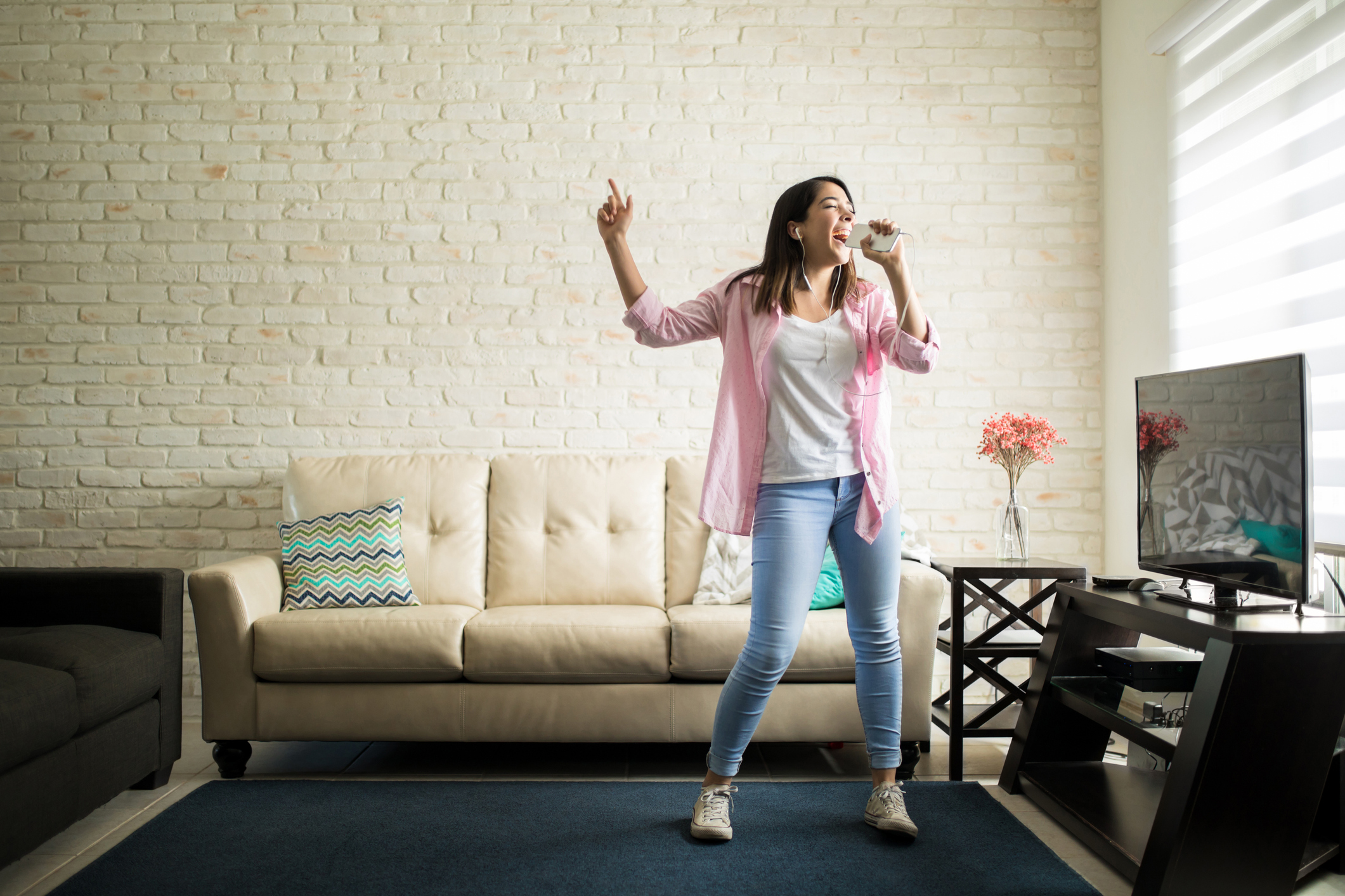 A young woman sings karaoke into her smartphone.