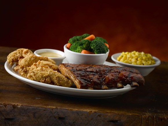 A plate with steak, fried chicken, and vegetables from Texas Roadhouse.