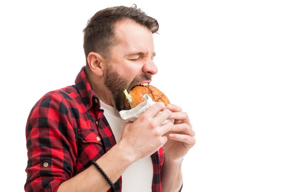 A man taking a big bite of a burger