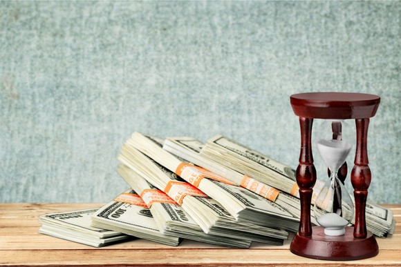 STacks of dollar bills next to sand timer
