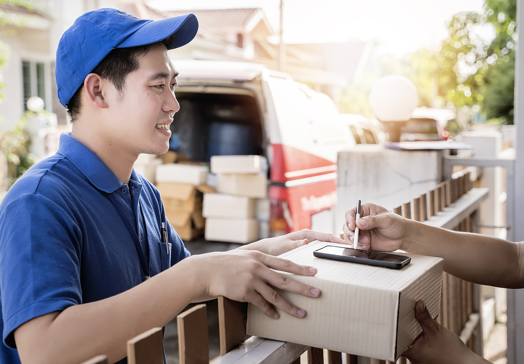 A young delivery man drops off a package and a customer signs for it.