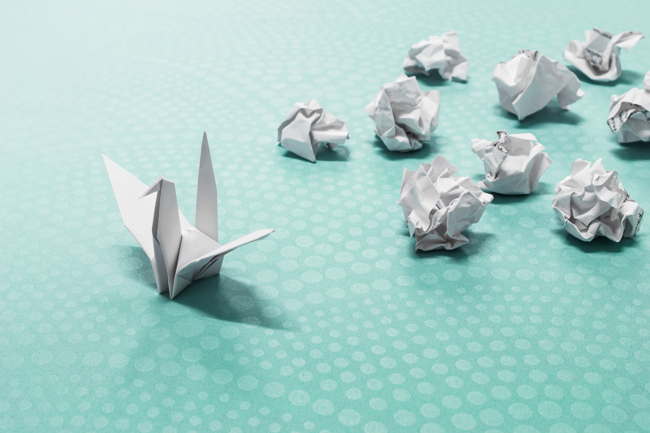 Several pieces of crumpled-up paper and an origami swan.