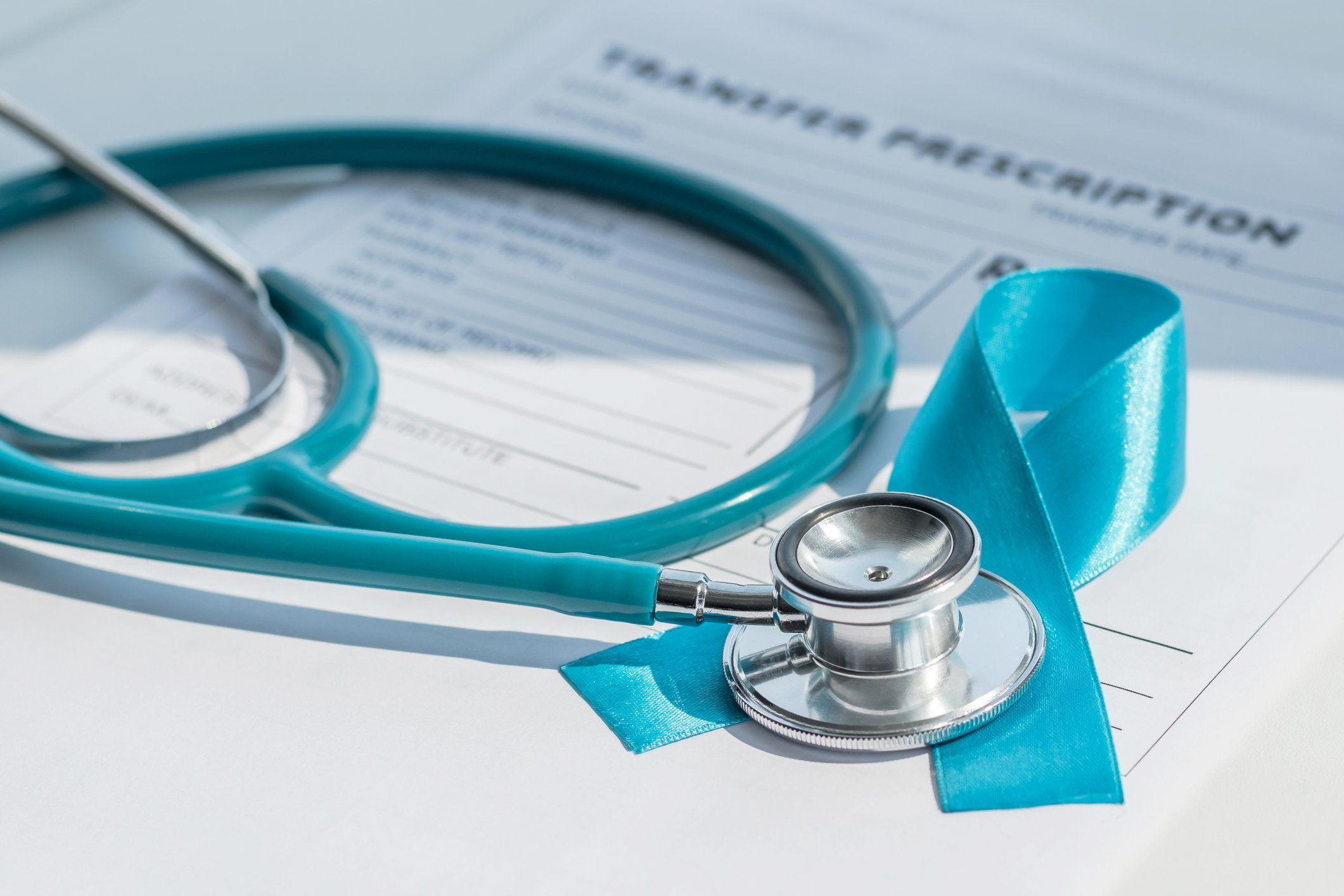 A stethoscope and a blue prostate cancer ribbon set on top of a prescription form.