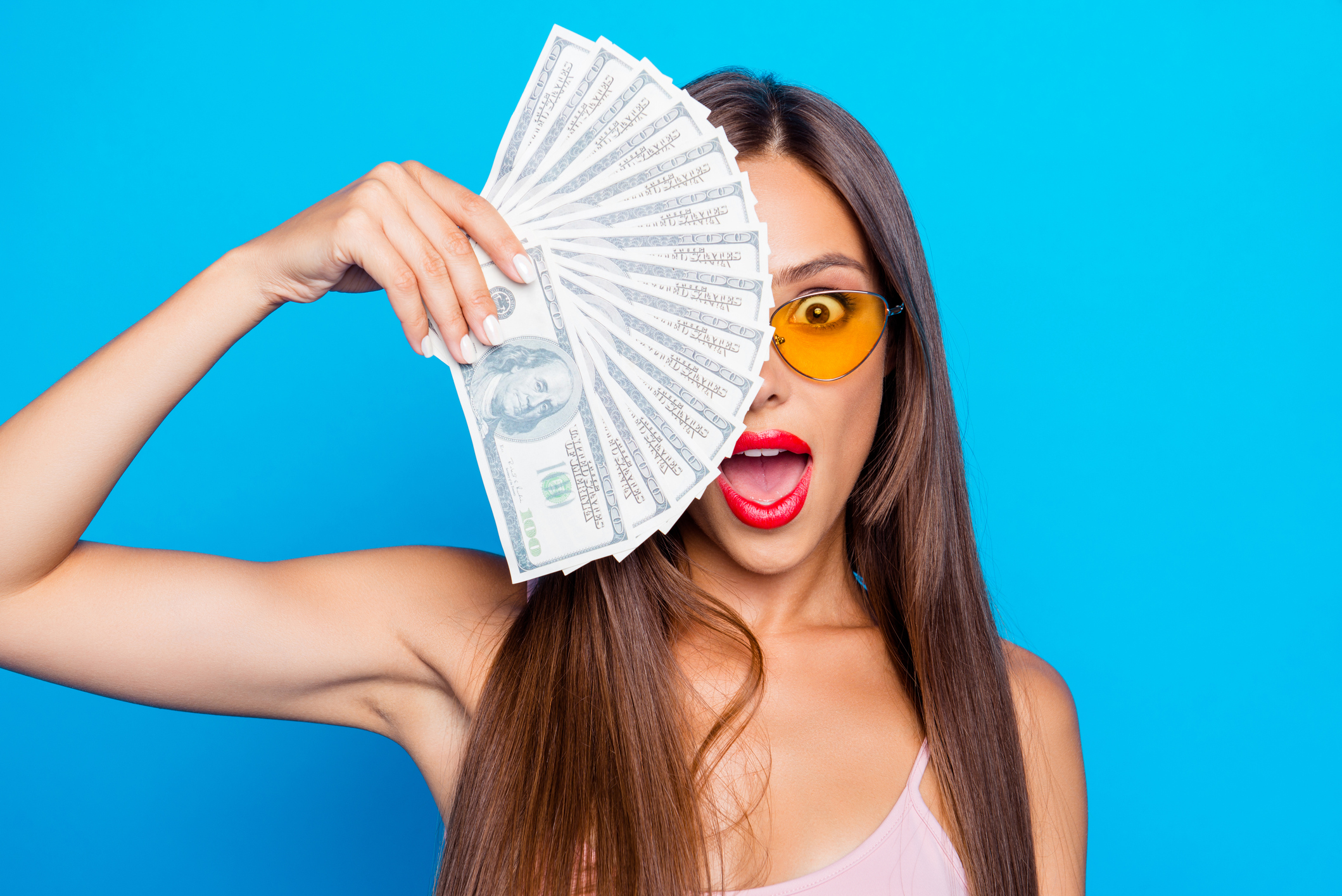 A woman fans herself with hundred dollar bills.