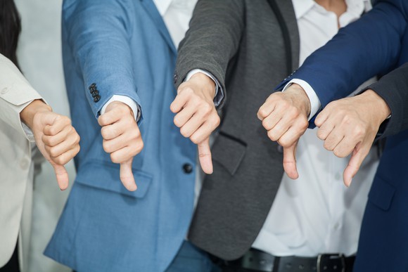 Businesspeople with thumbs down