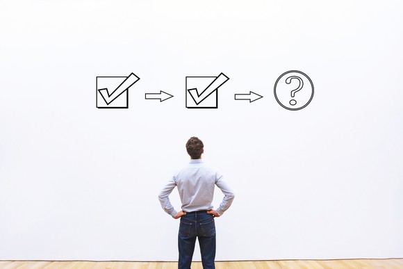 A person looking at two checked boxes leading to a question mark.