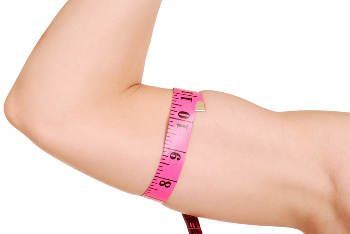 Close-up of a flexed well-conditioned woman's arm with a tape measure around it.