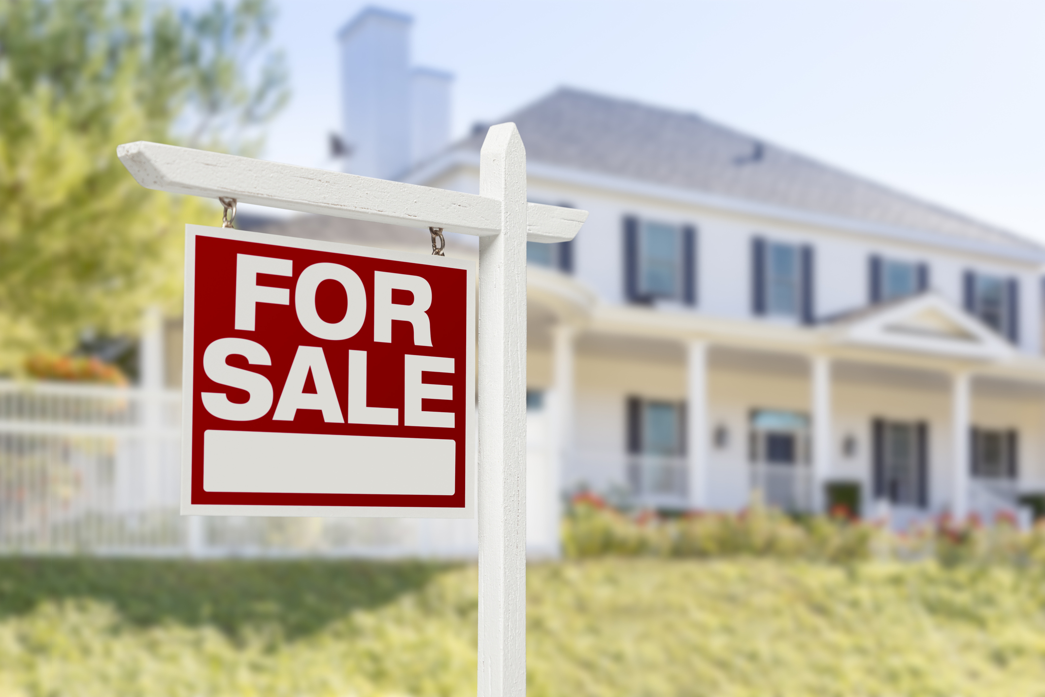 Large white house with For Sale sign on the front lawn
