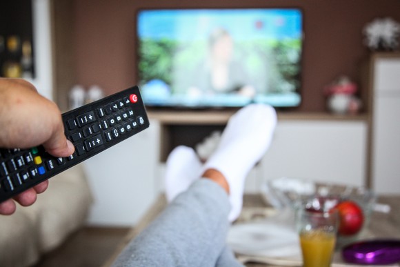 A man holding a remote in front of the TV.