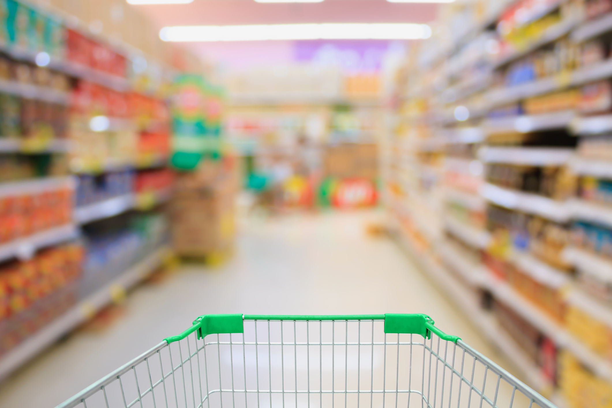 A grocery cart in an empty grocery aisle