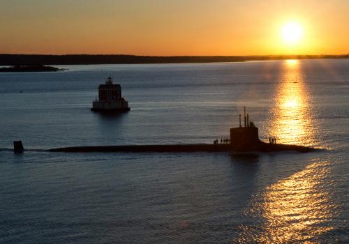 A submarine in front of a setting sun.