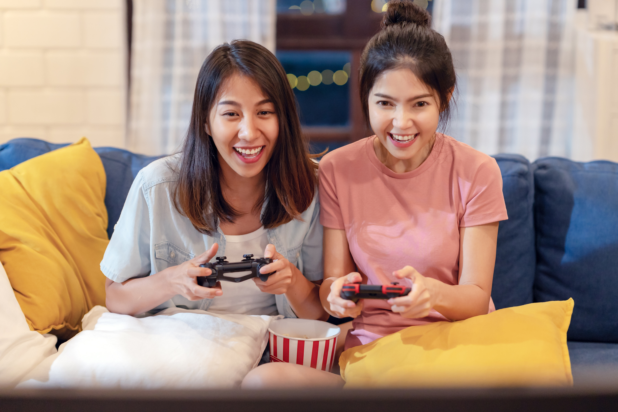 Two Girls Sitting On A Couch Playing a Video Game