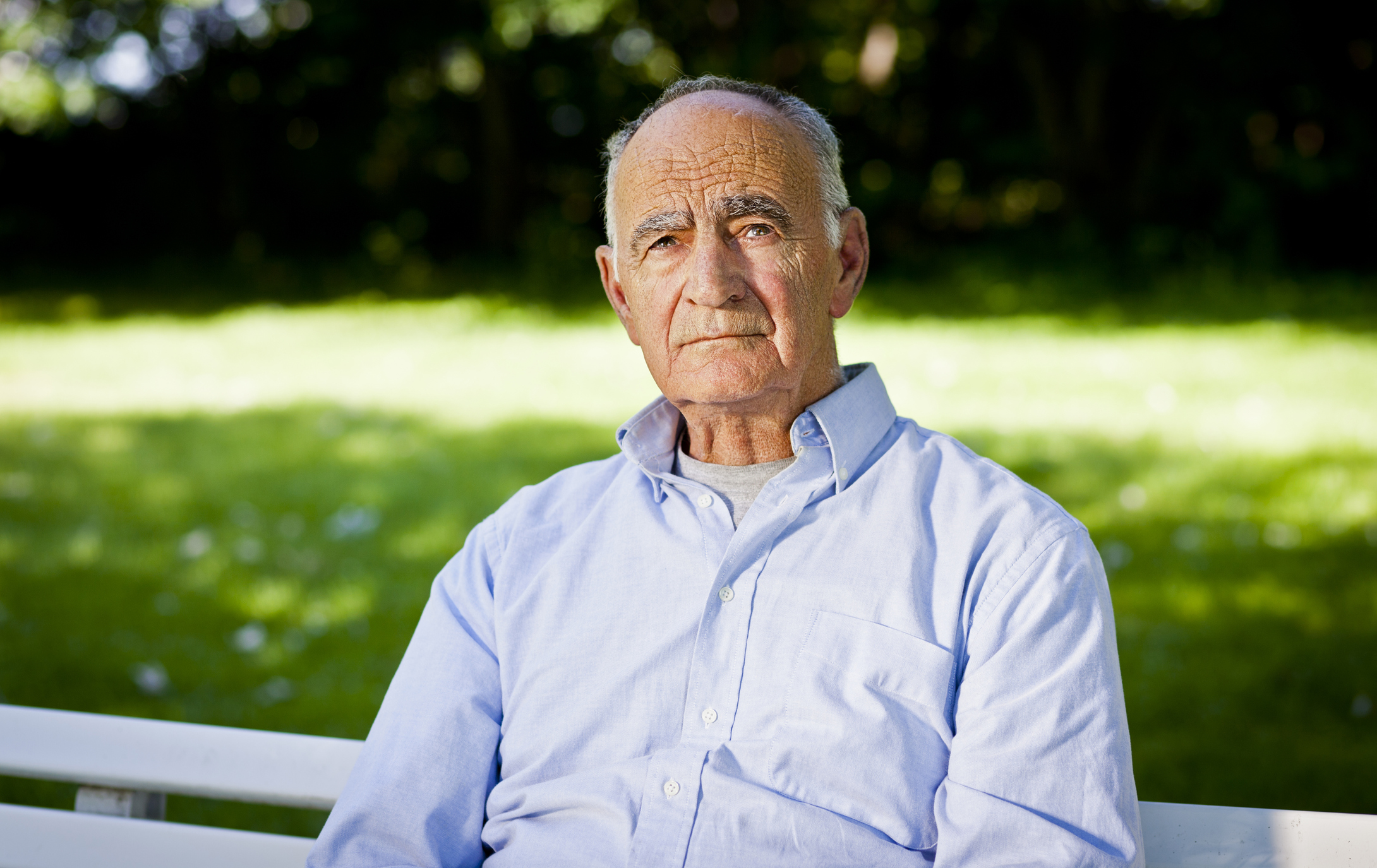 Older man with sad expression sitting on a bench
