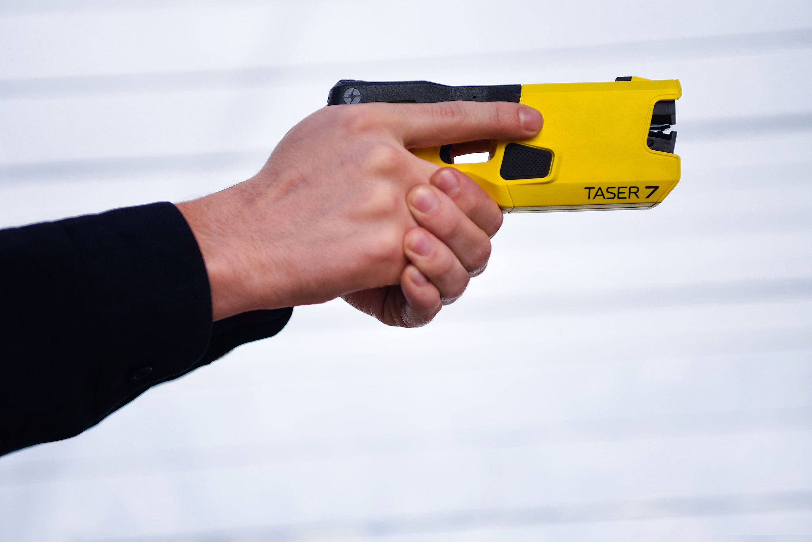 A person holding and aiming an Axon Taser 7