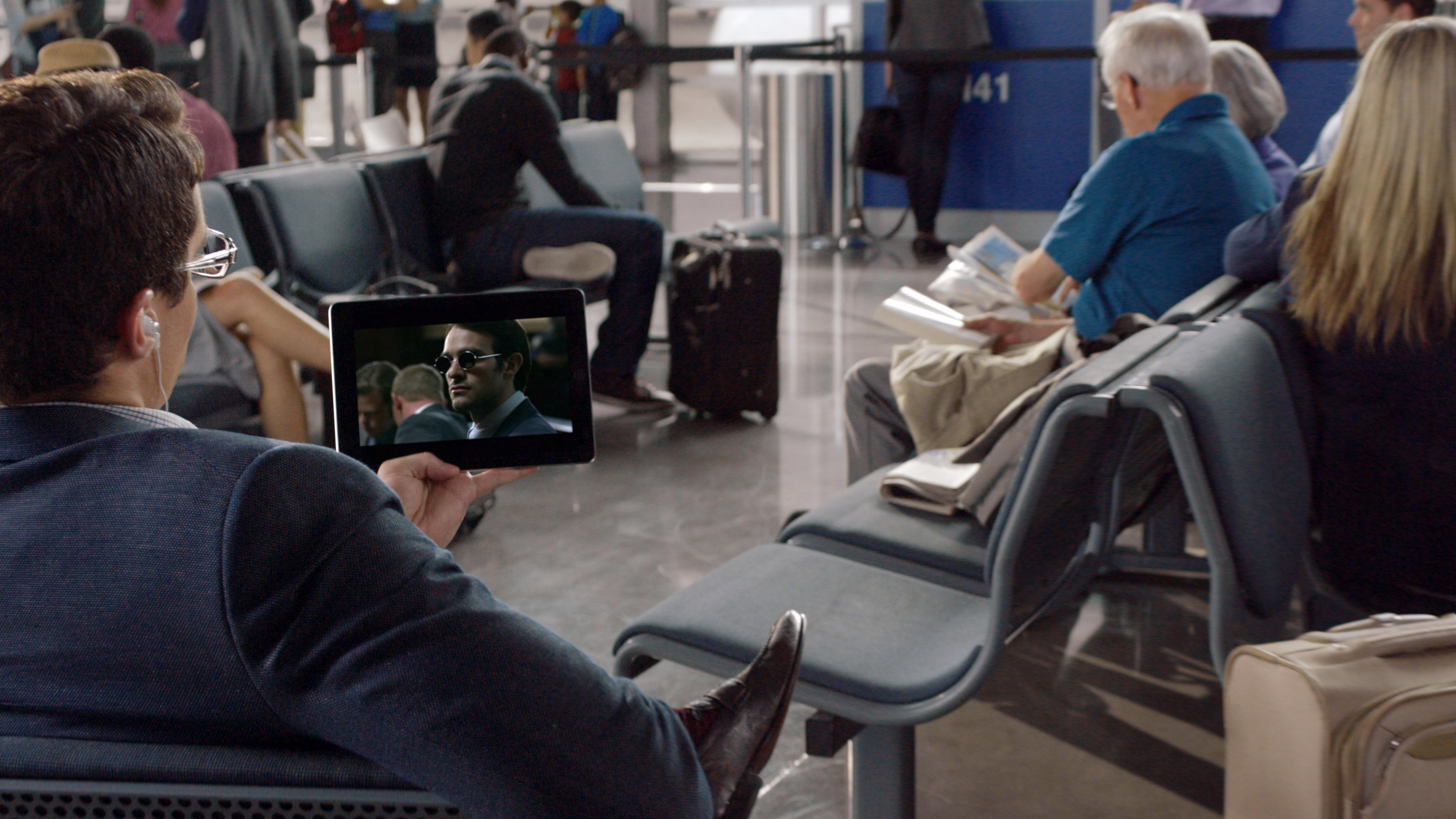 A man watching Netflix on a tablet in an airport.