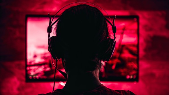 A person wearing headphones and looking at a monitor.