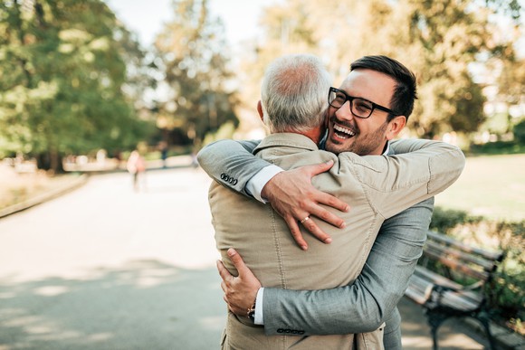 Older man and younger man embracing