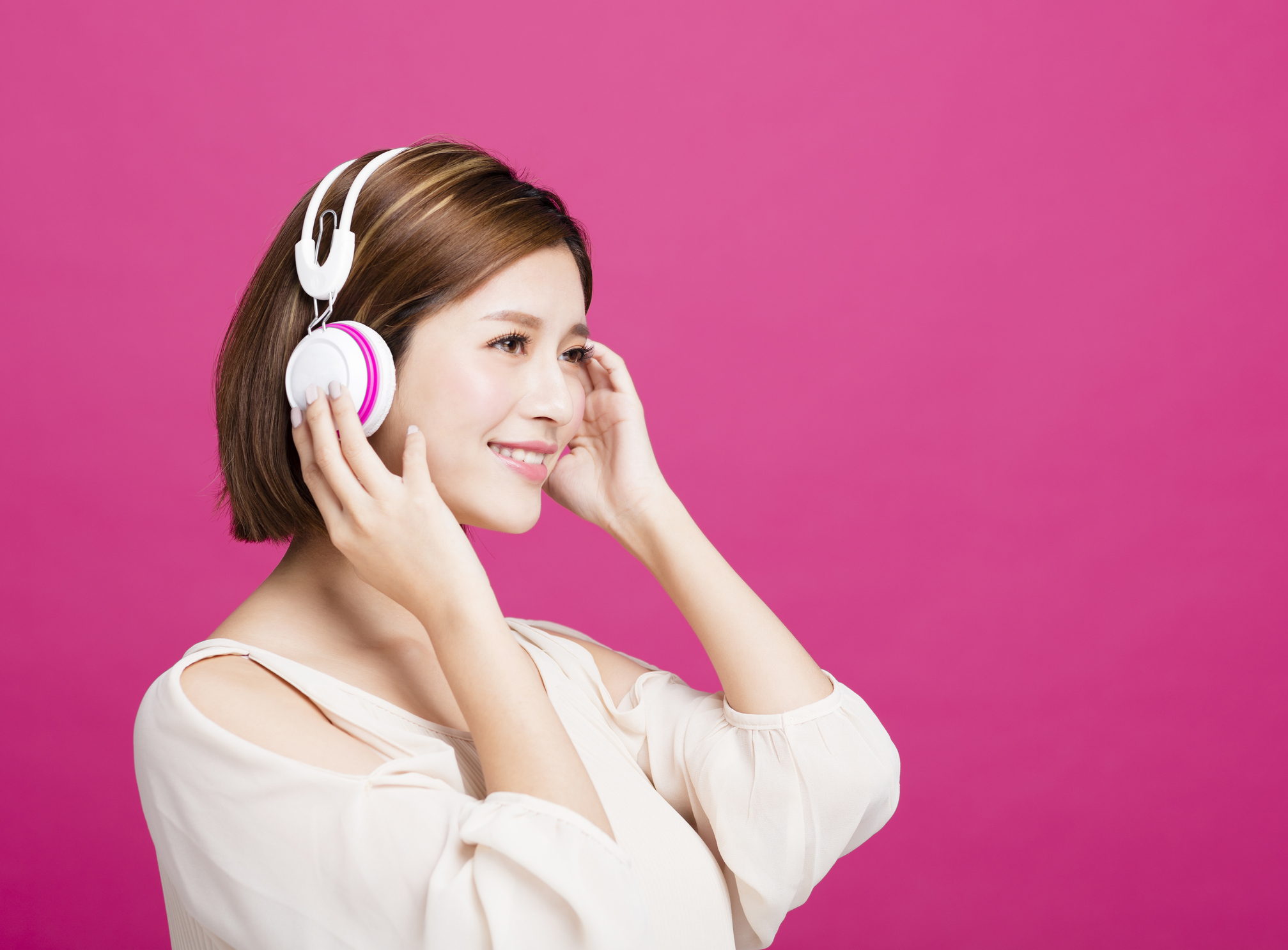 A young woman listens to music on her headphones.