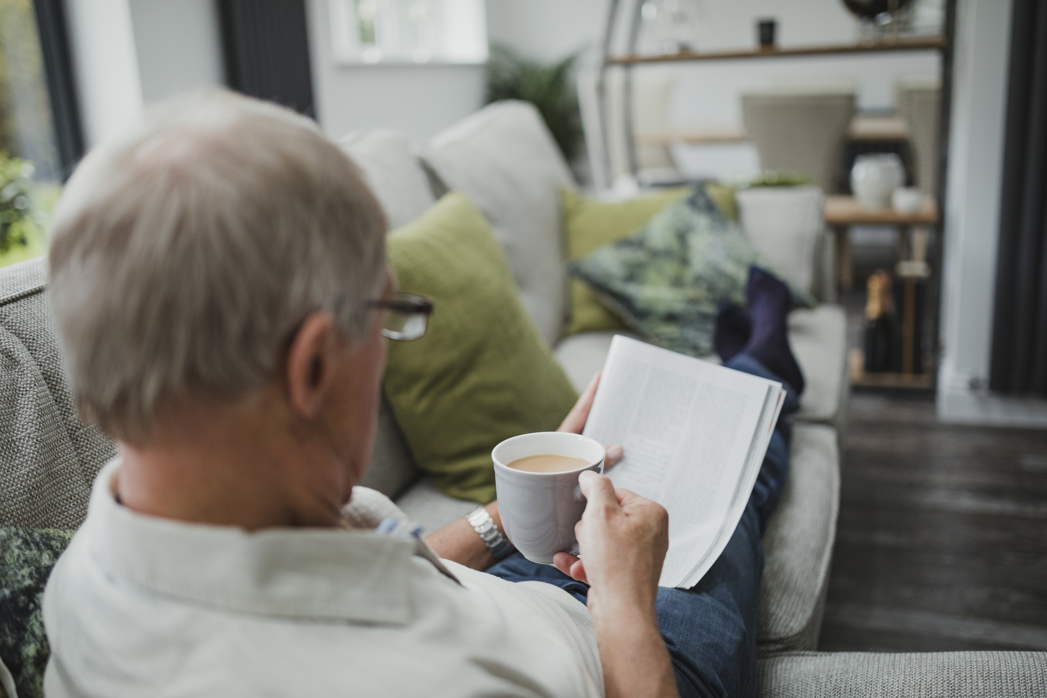 Older man reading a magazine while holding a mug